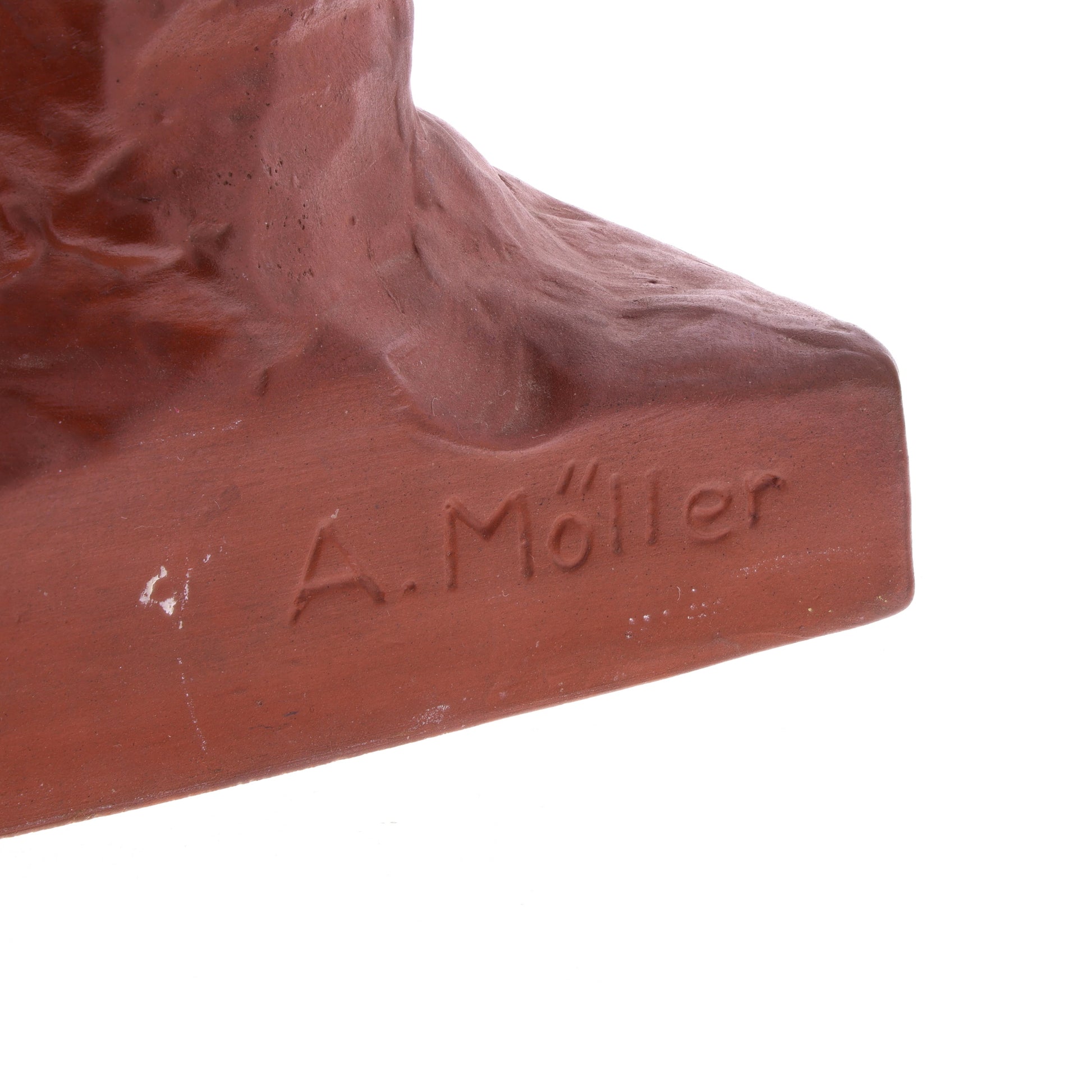 Close-up of a terracotta sculpture with 'A. Moller' engraved on a white background
