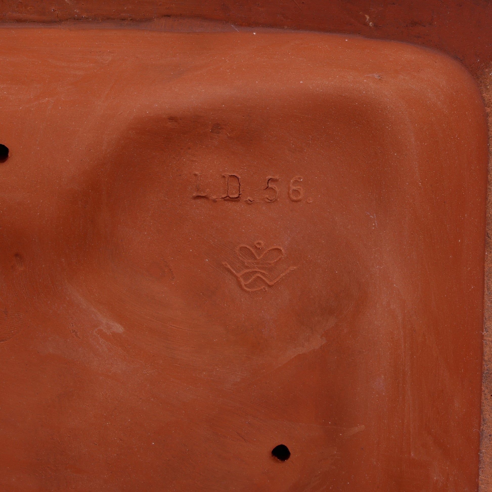 Terracotta sculpture with 'L/D. 56' and a crown interlaced with 'W G'.